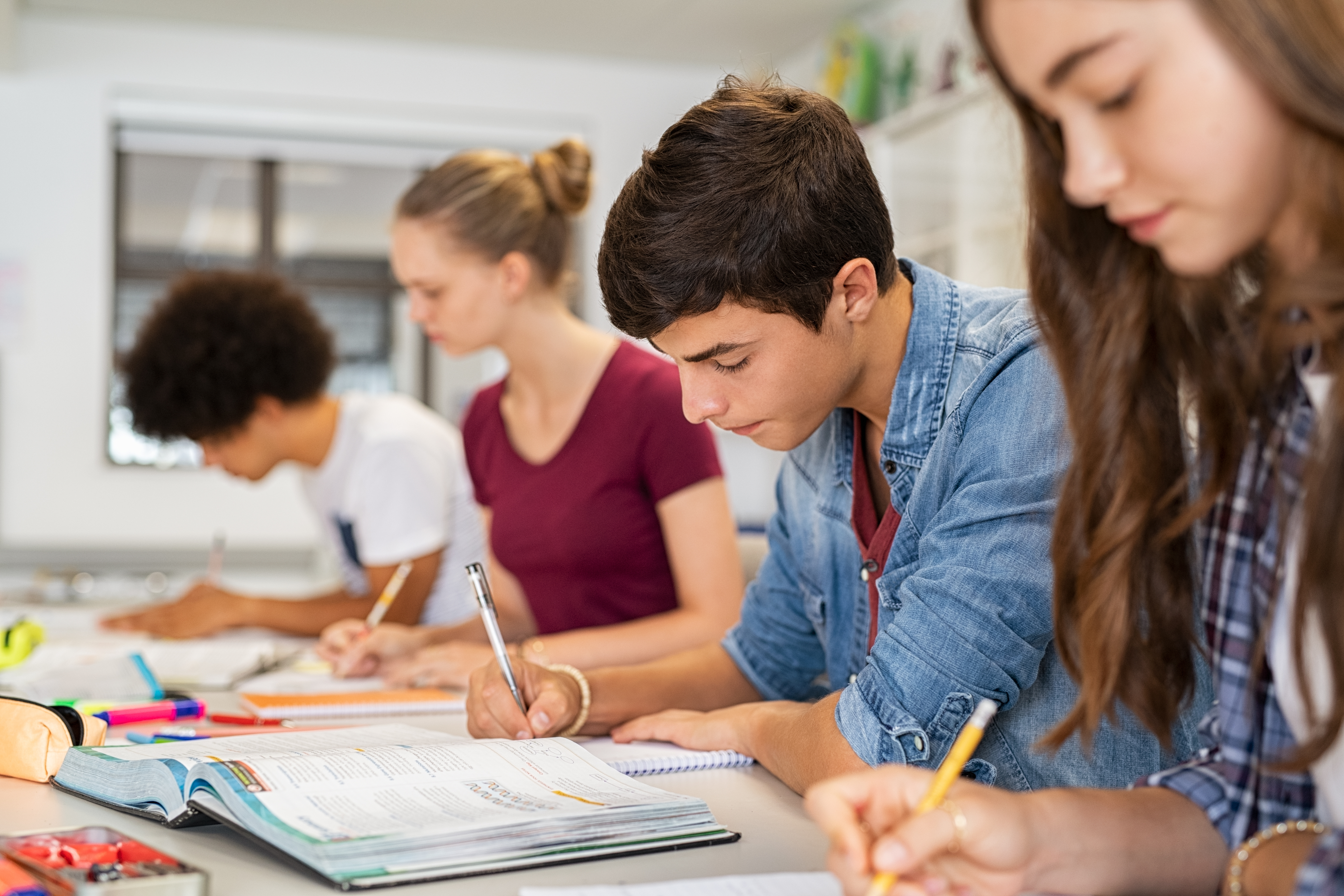 four high school students writing